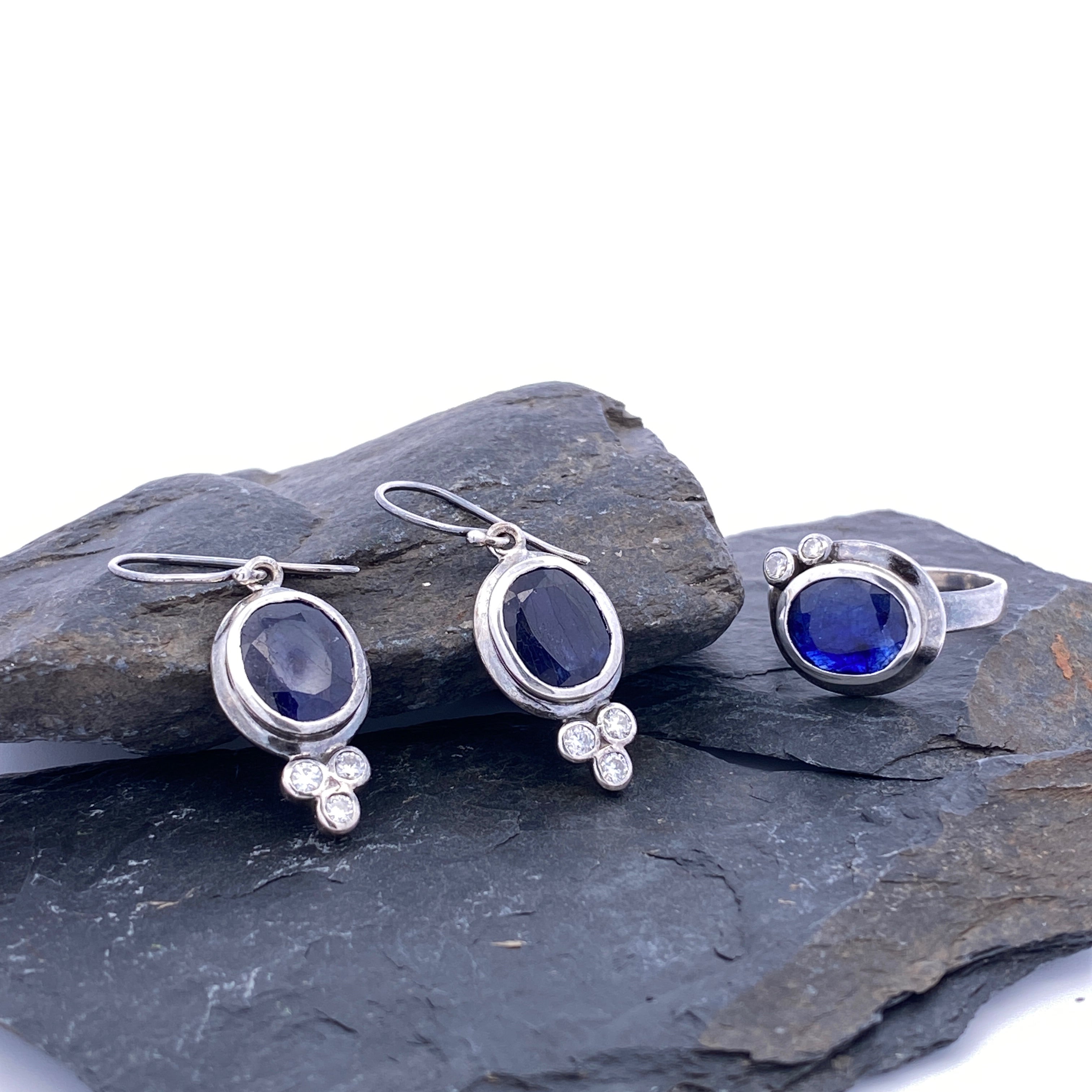 Silver jewelry set with blue gemstones on a stone surface