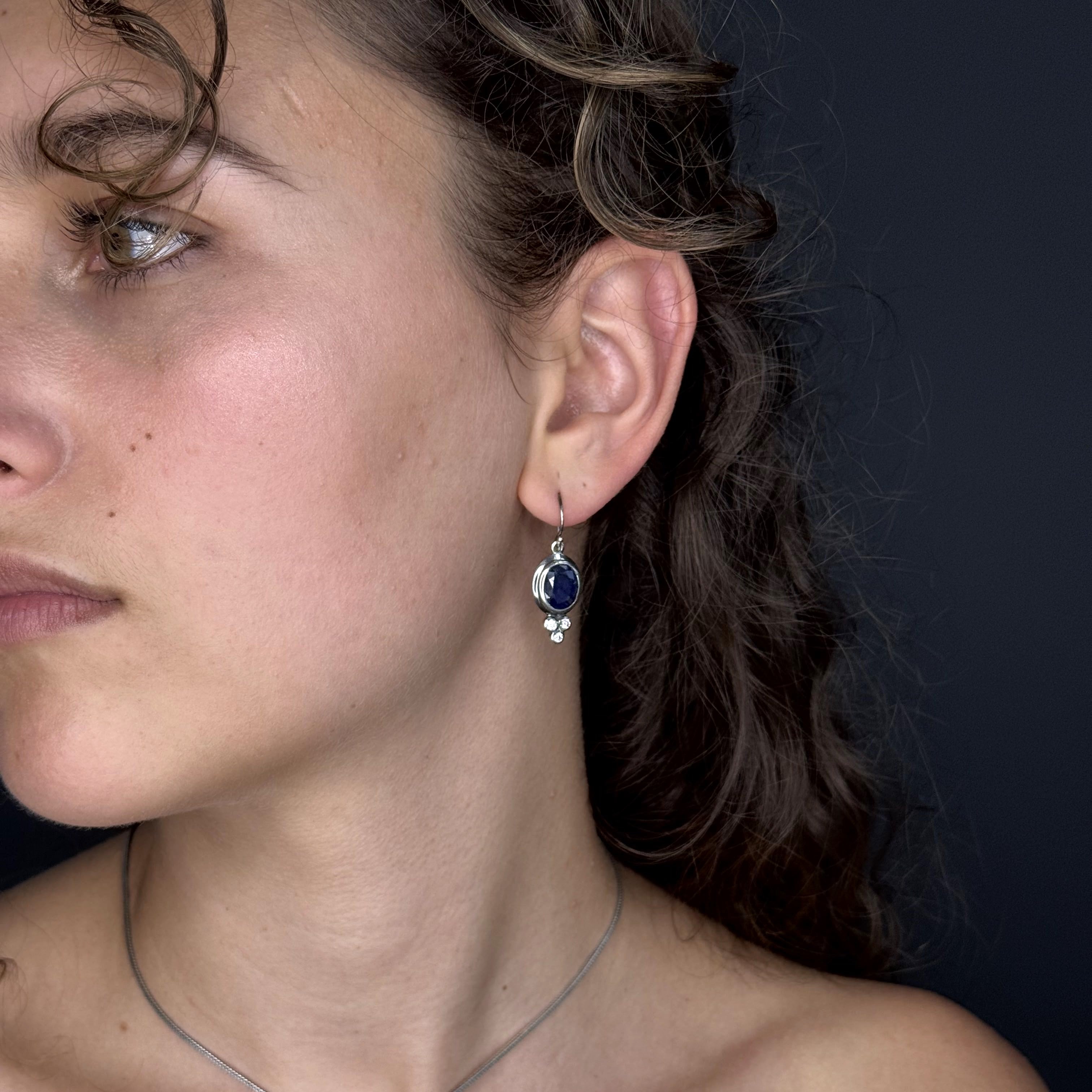 Close-up of a woman wearing a blue gemstone earring against a dark background