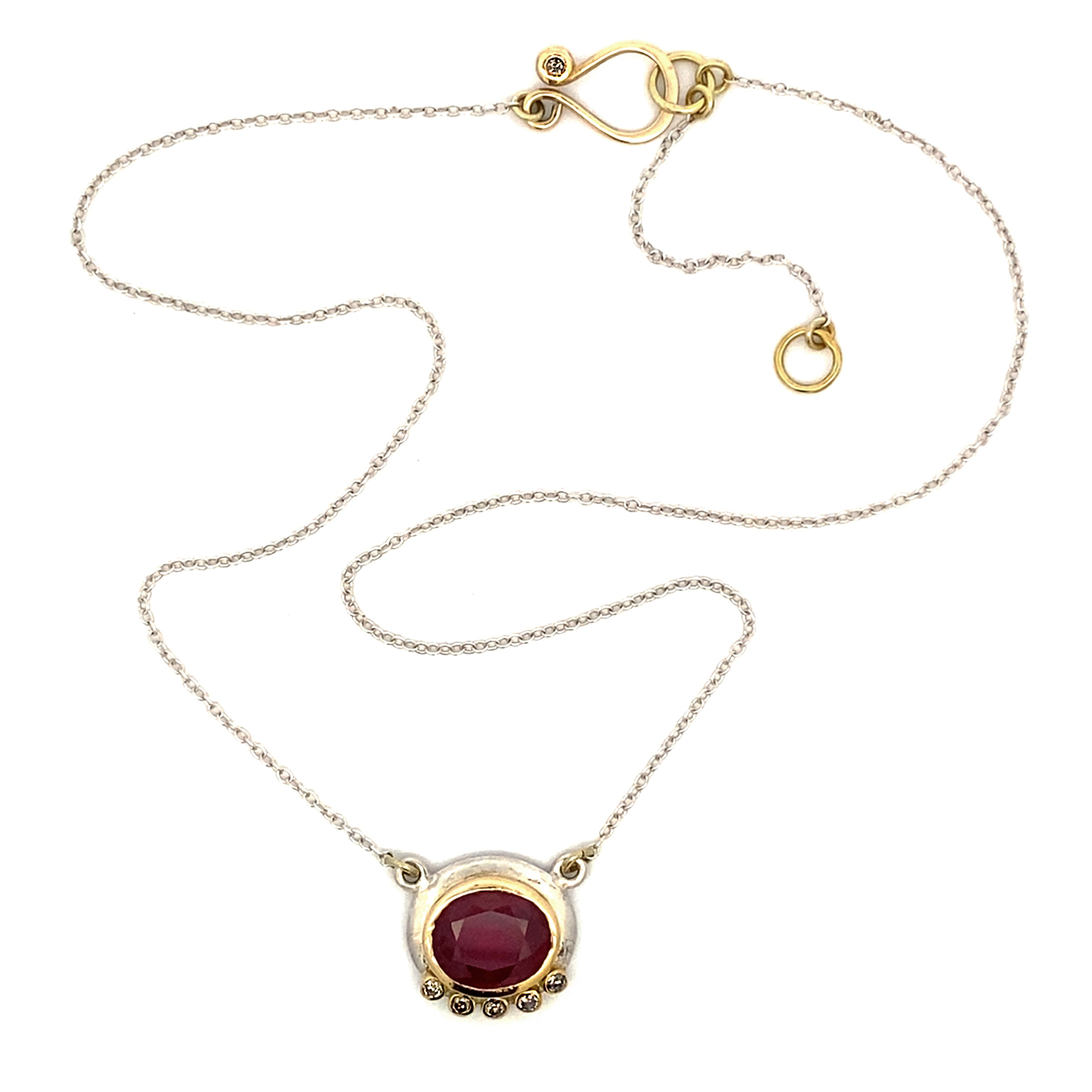 Gold necklace with a red gemstone pendant on a white background