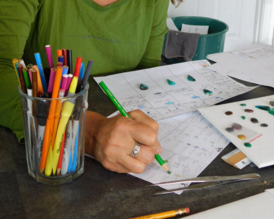 Q Evon in green shirt working on a drawing project with colored pencils and paper.