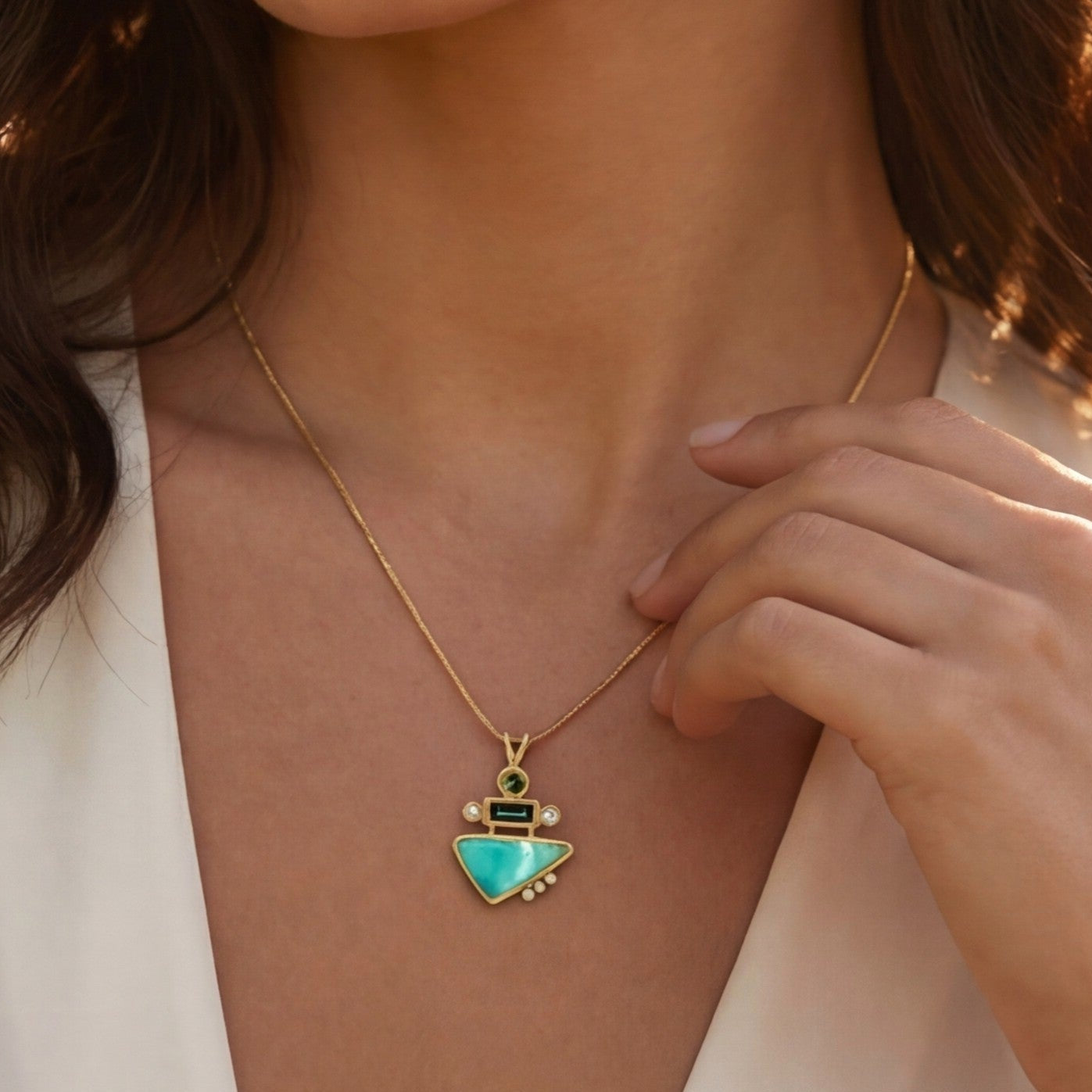Woman wearing a necklace with a green pendant in a natural setting