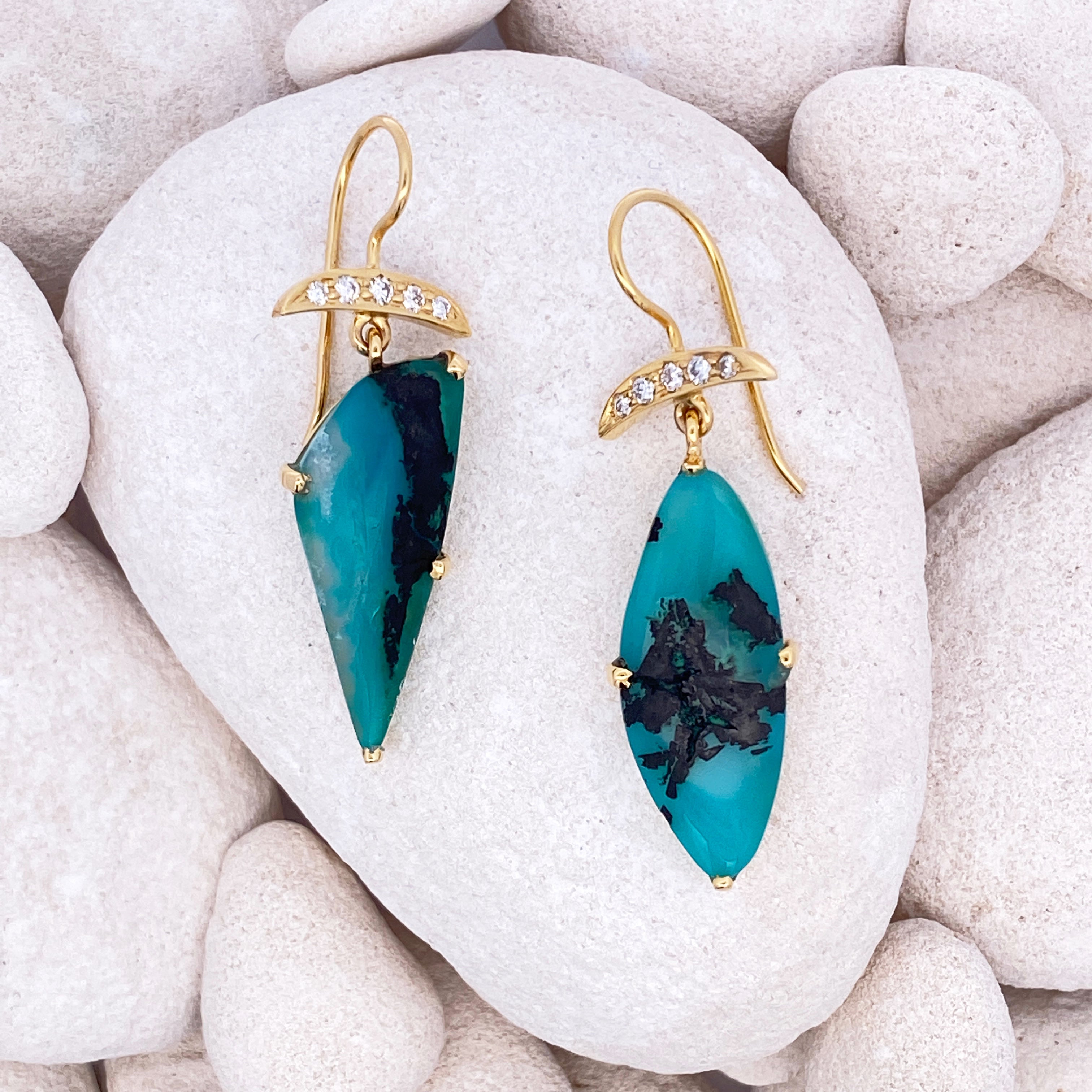 Gold and turquoise earrings on white stones