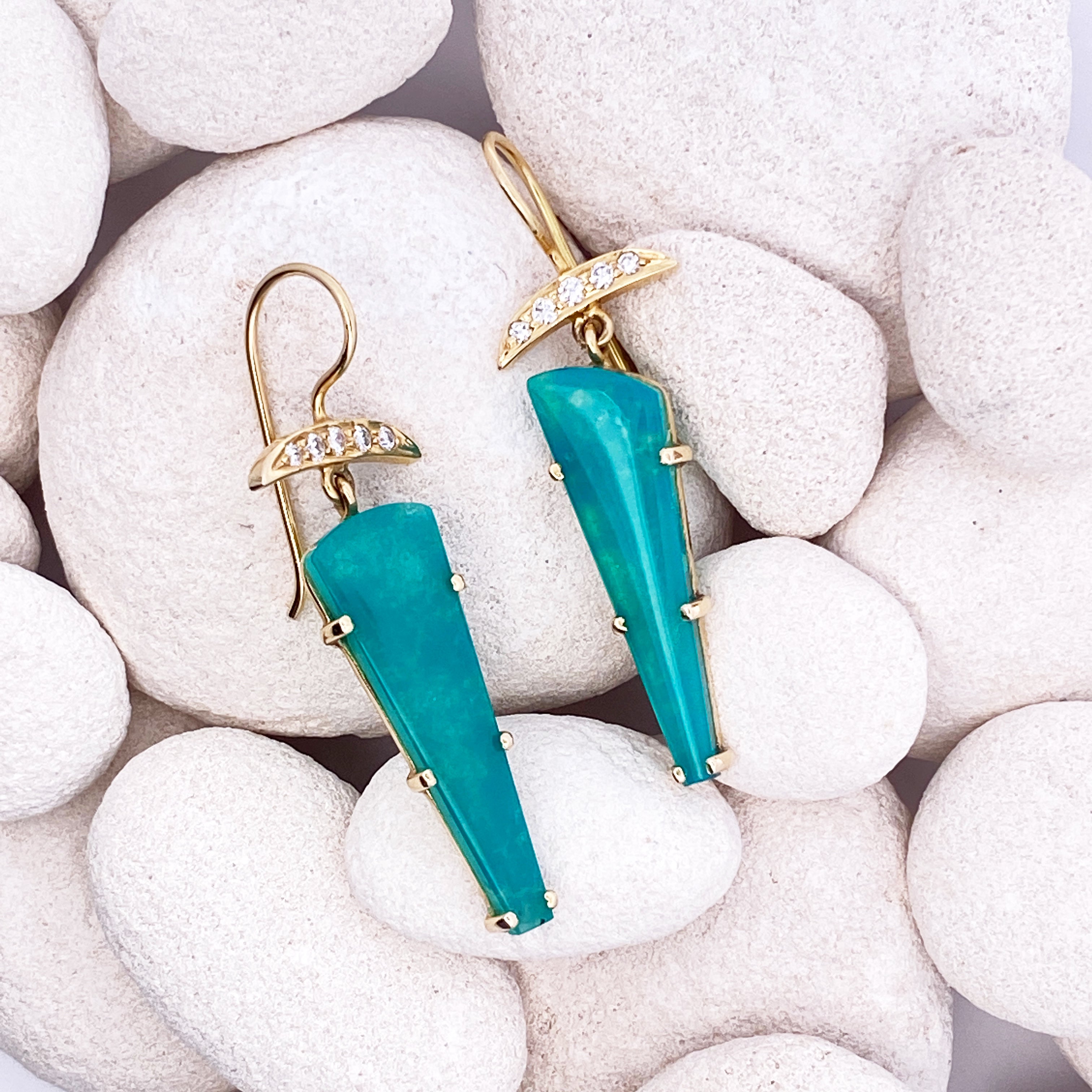 Turquoise earrings with gold accents on white pebbles