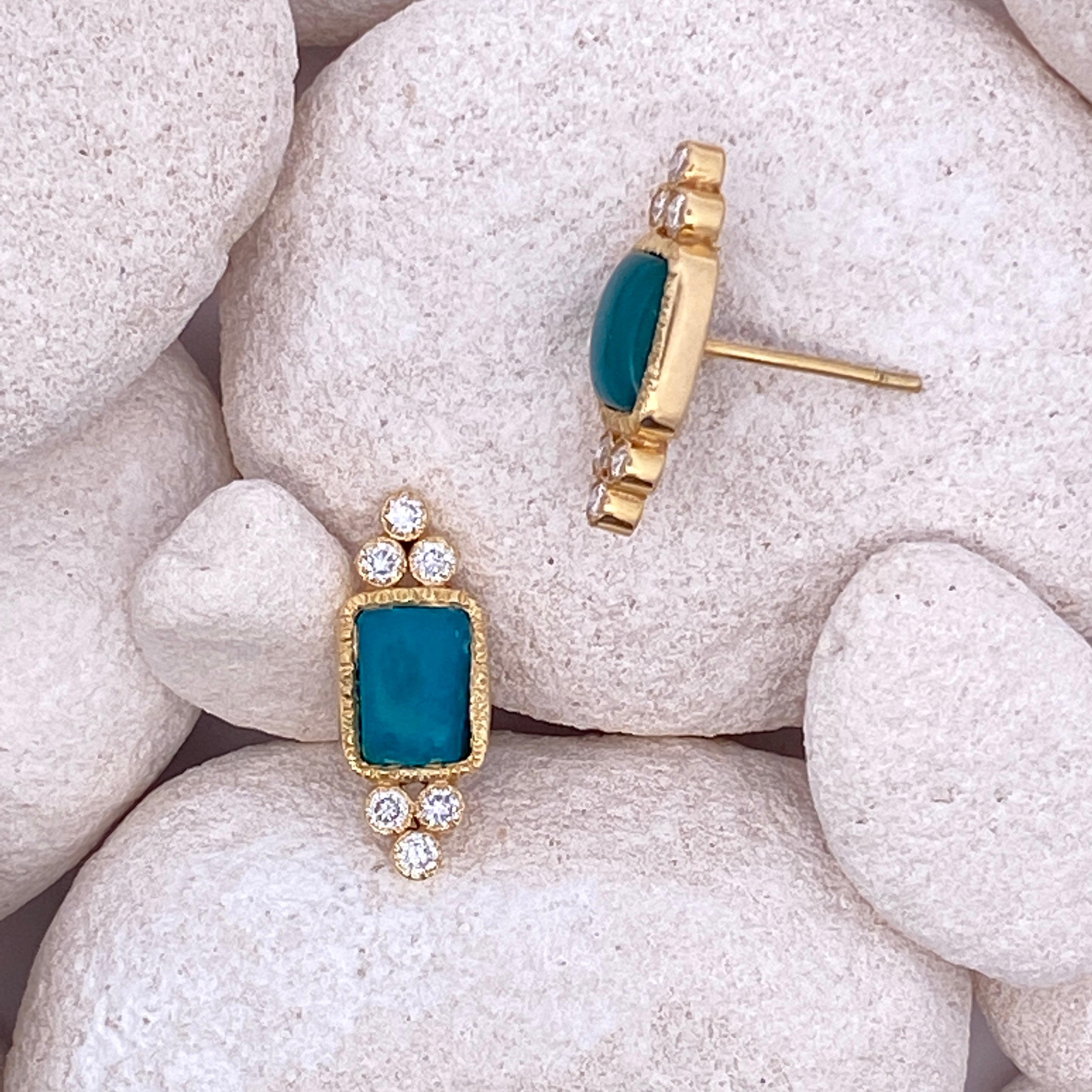 Gold and teal earrings on white stones