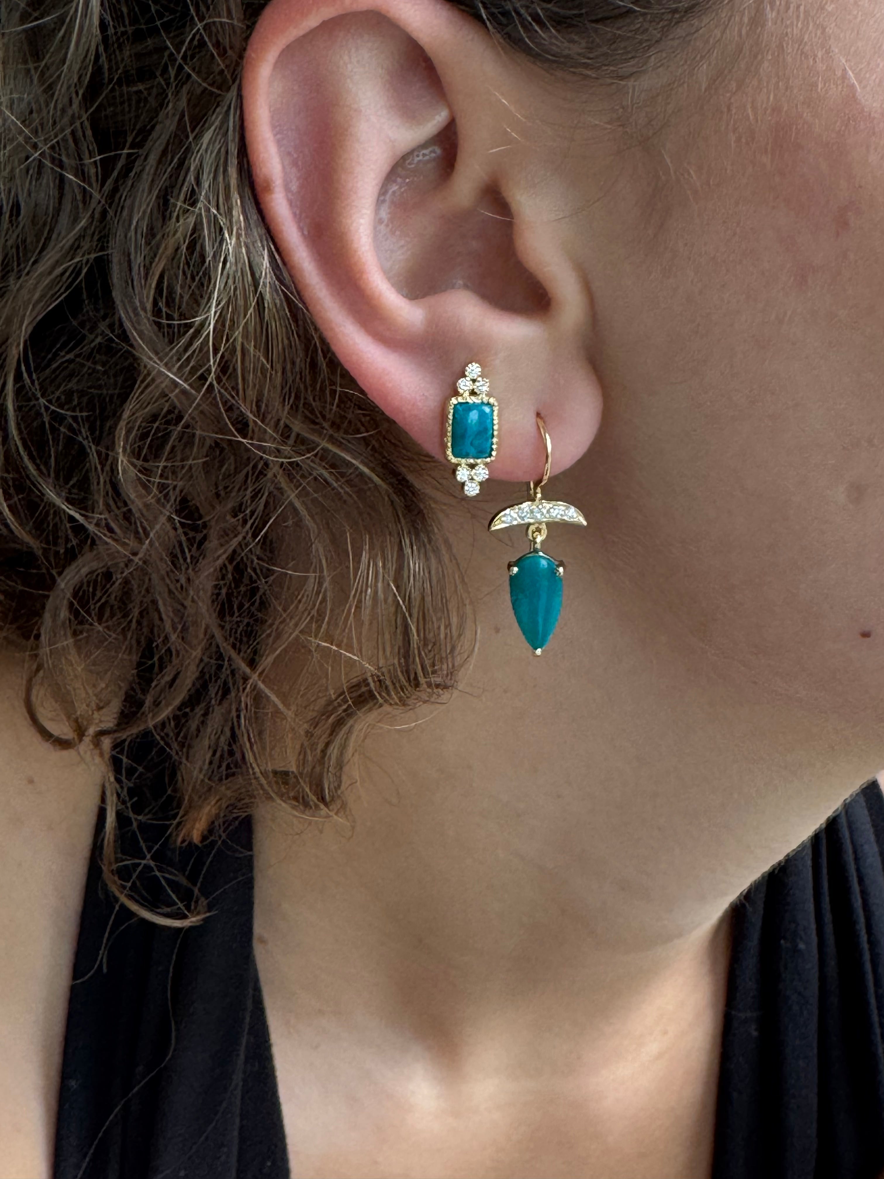 Close-up of an ear with turquoise gemstone earrings.