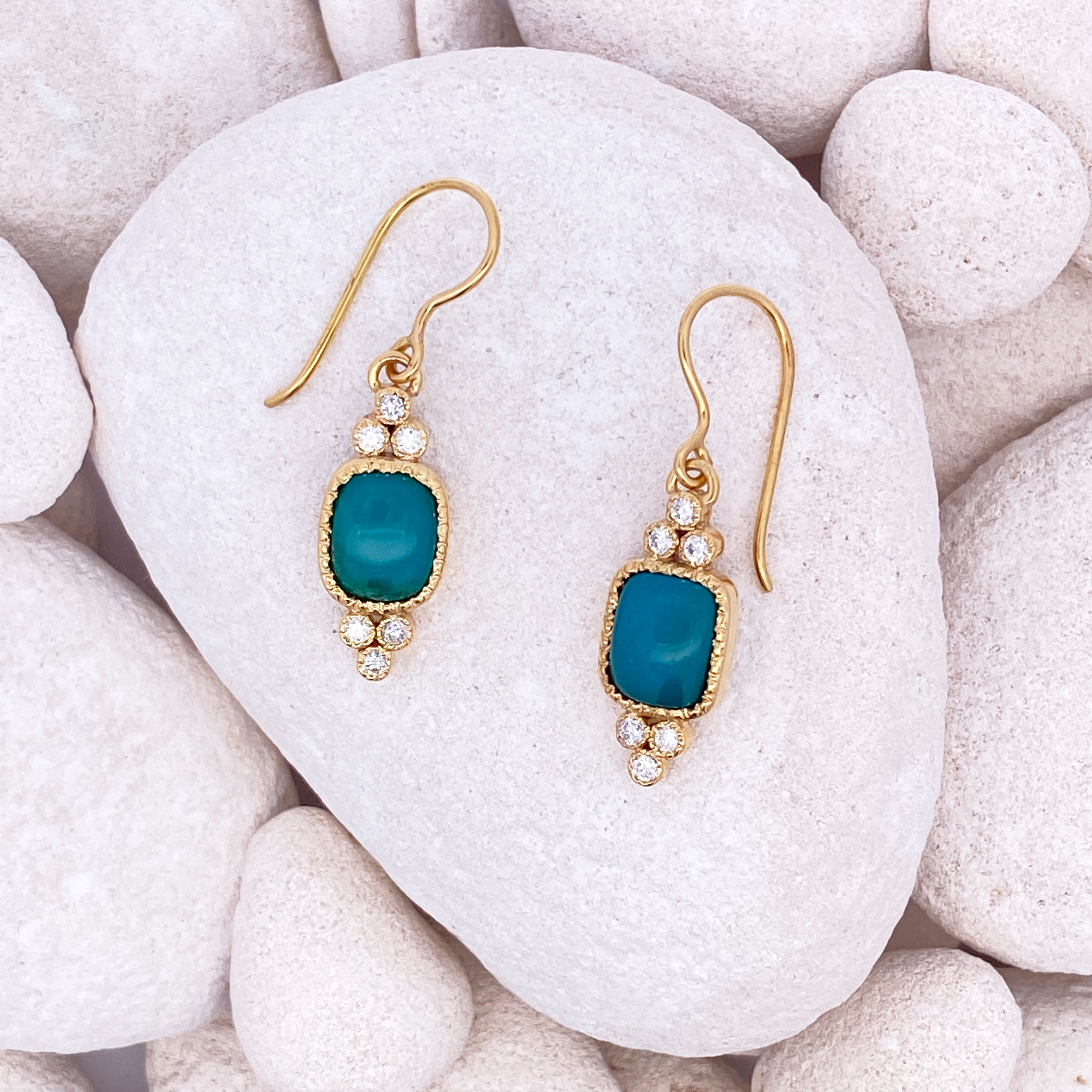 Gold earrings with blue stones on a white stone background