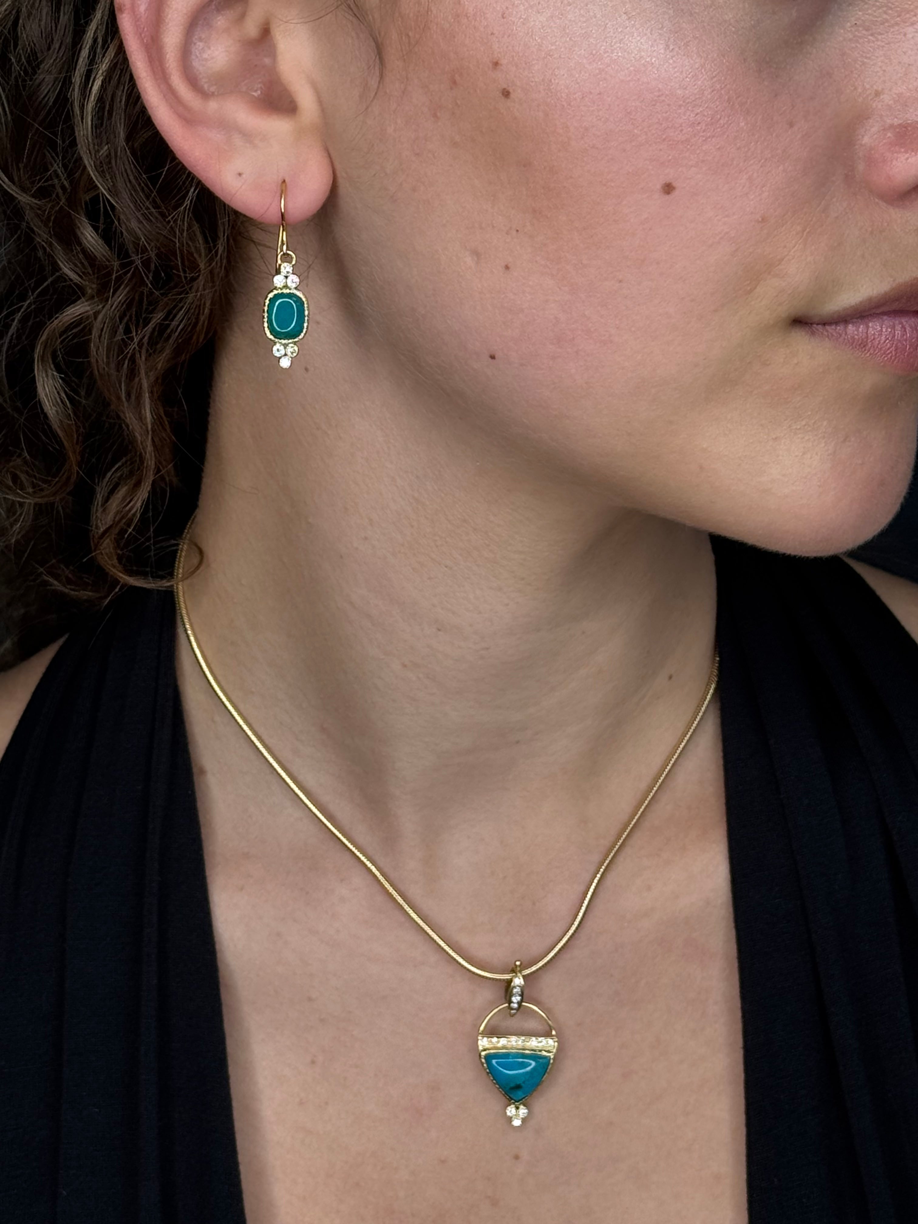 Close-up of a person wearing a gold necklace with turquoise stones.