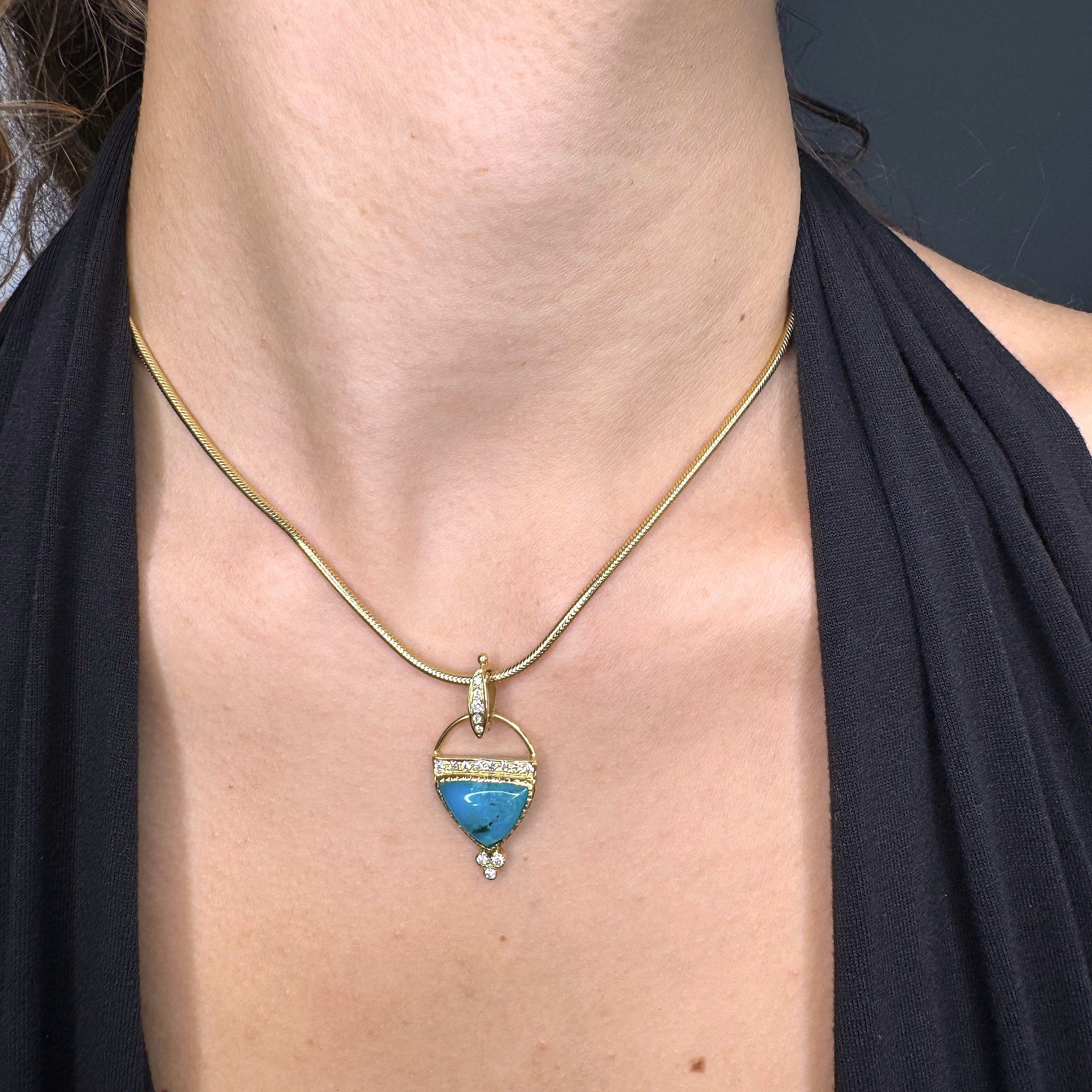 Necklace with a blue pendant worn by a person against a dark background