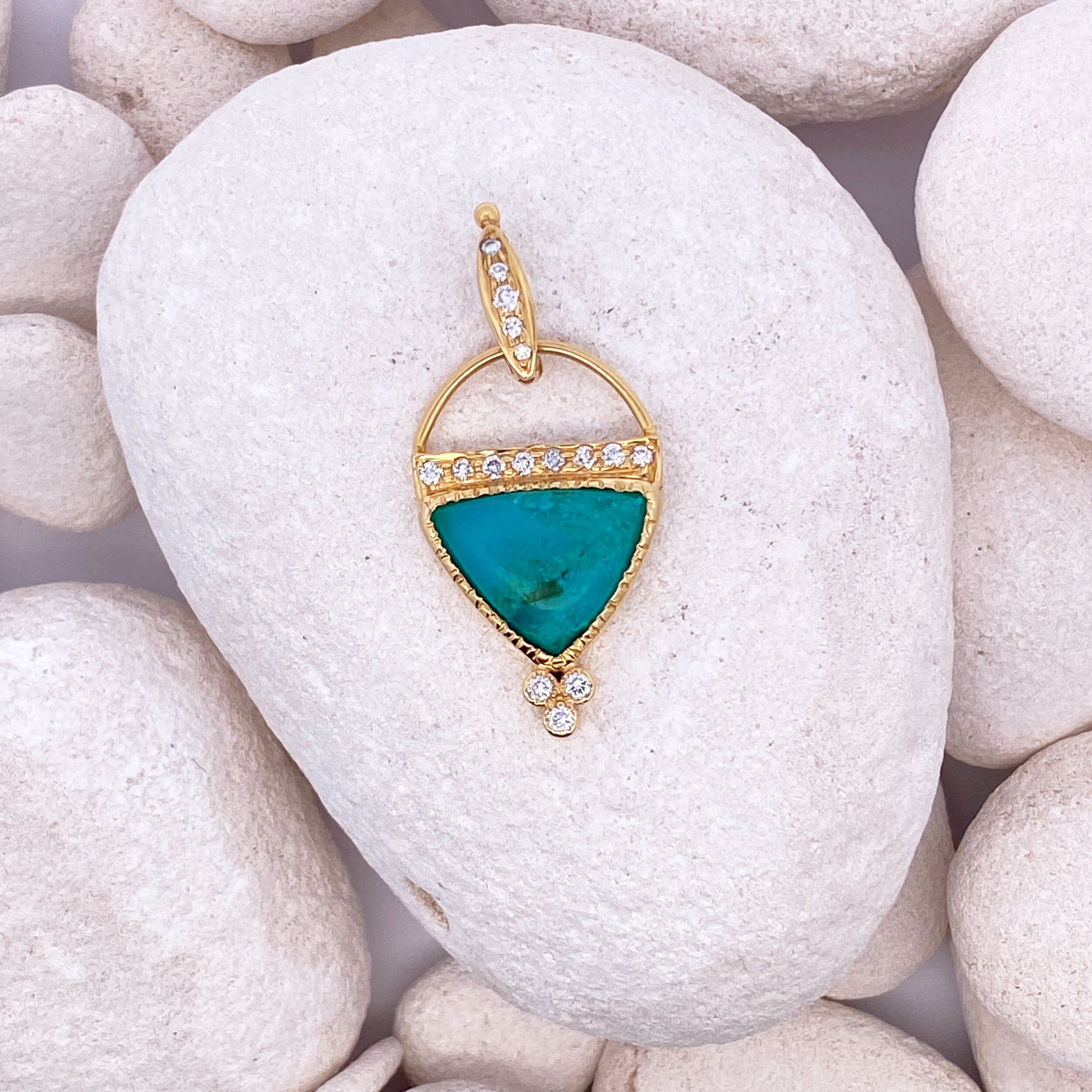 Gold pendant with a turquoise stone on a white stone surface