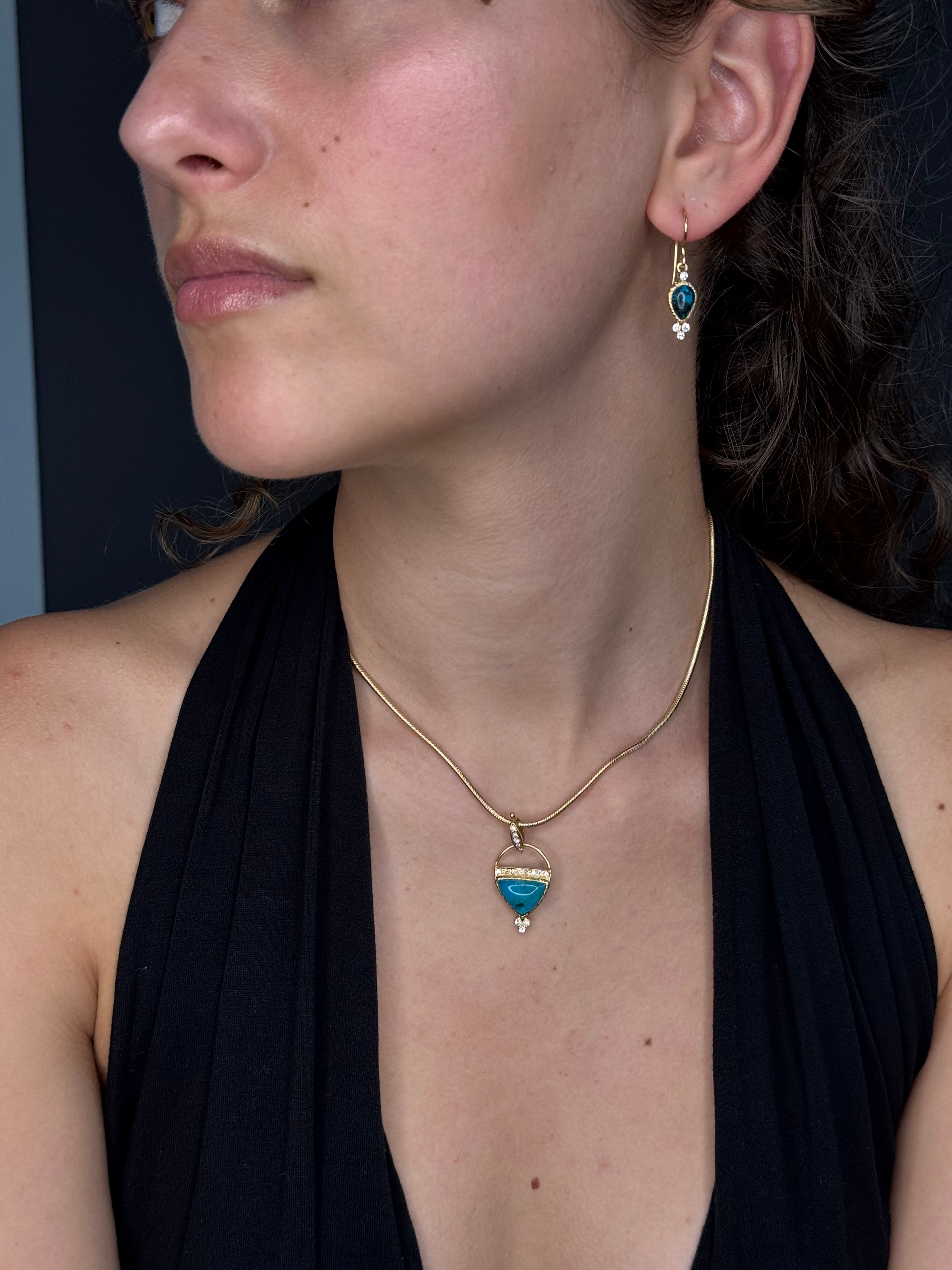 Close-up of a person wearing a gold necklace with a blue pendant.