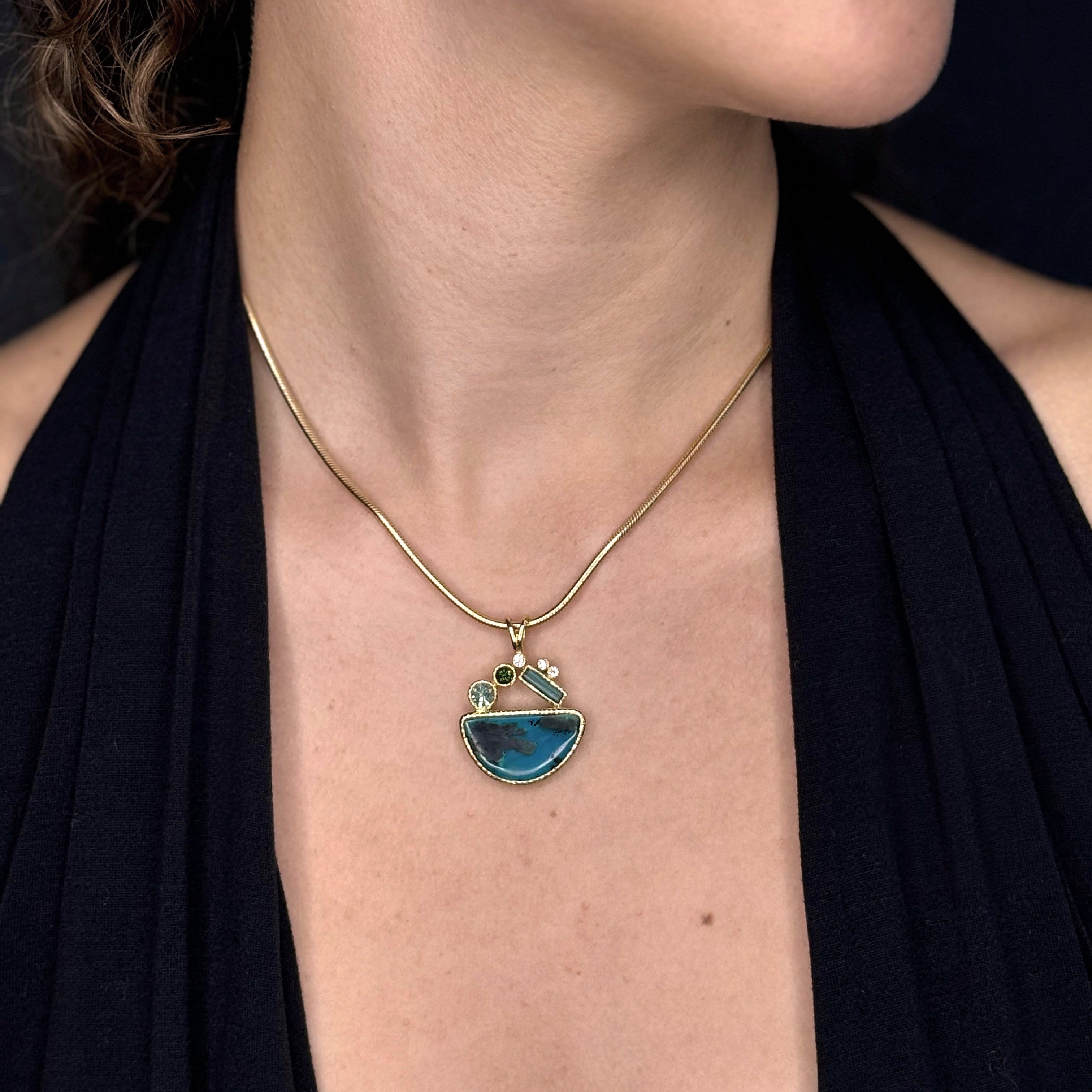 Necklace with a blue pendant worn by a person against a black background