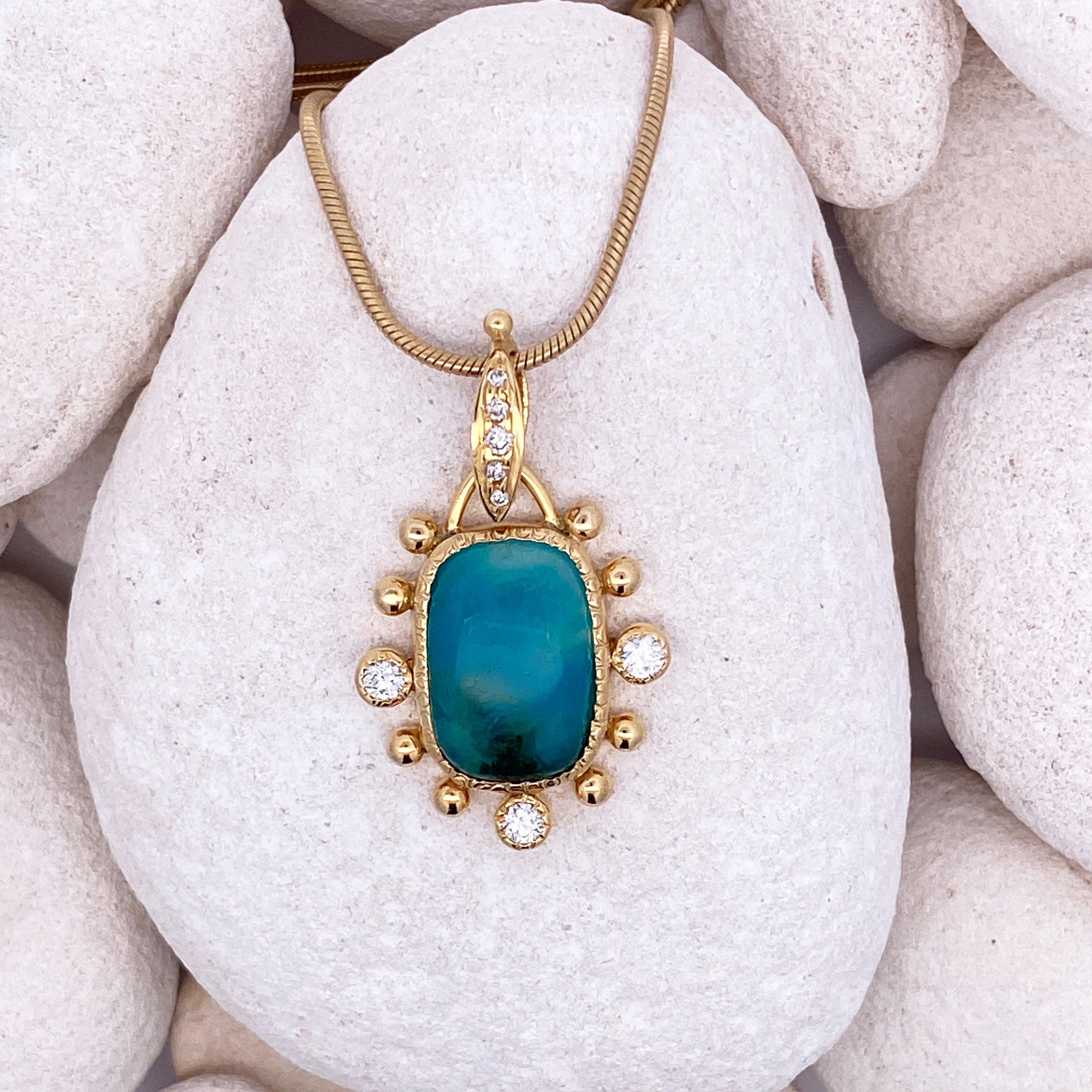 Gold necklace with blue pendant on white pebbles