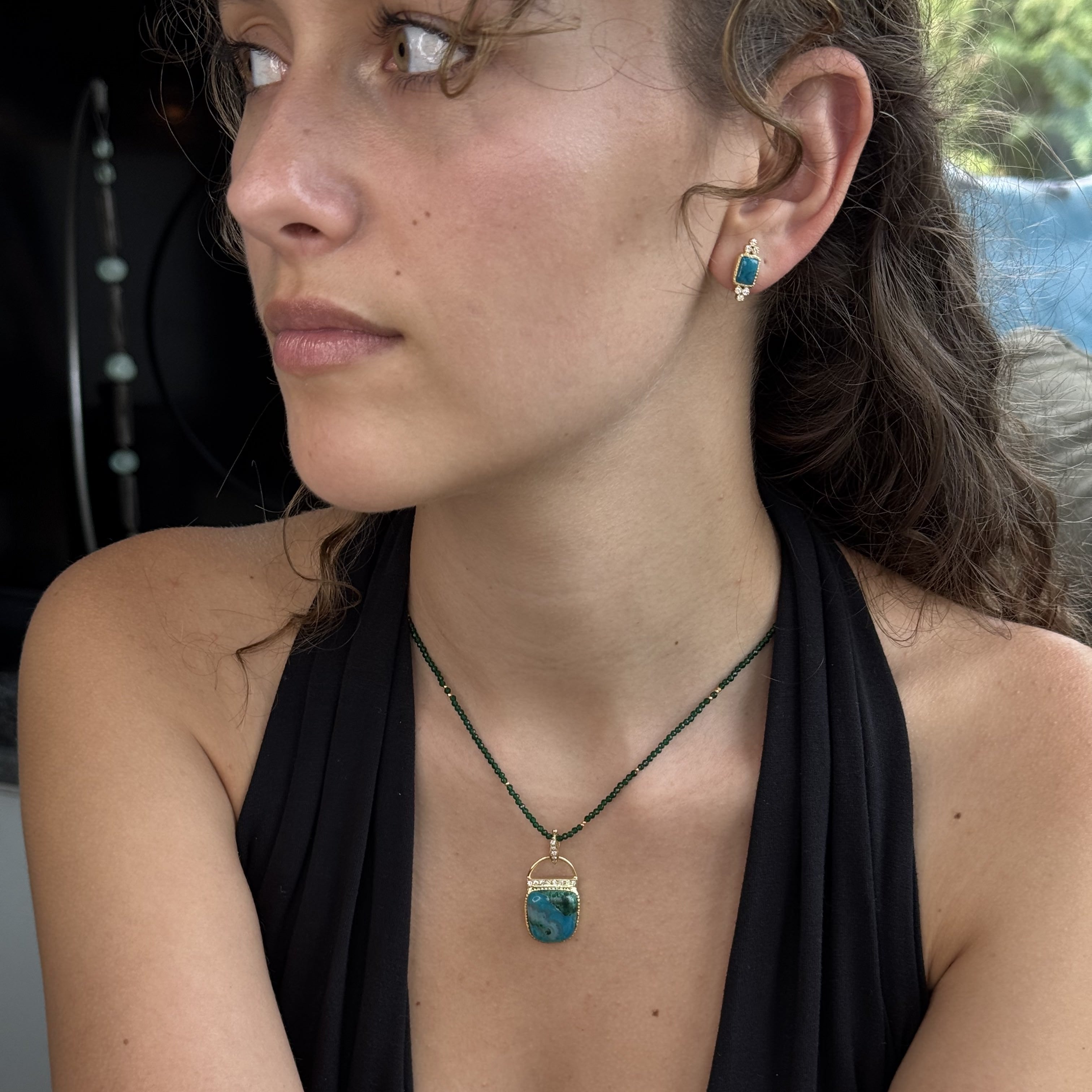 Woman wearing a necklace and earrings with a blurred background