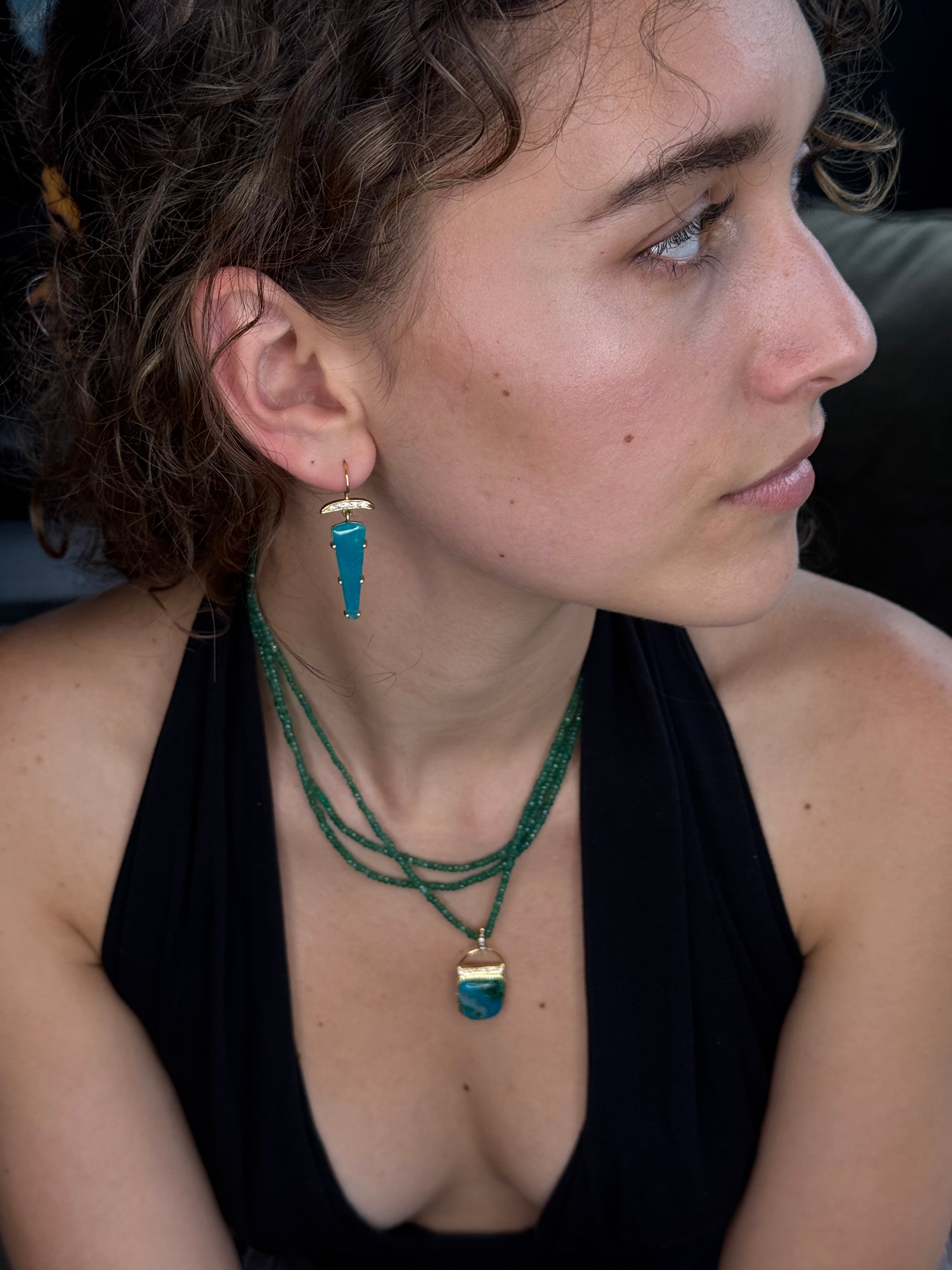 Close-up of a person wearing a green necklace with a blue pendant.