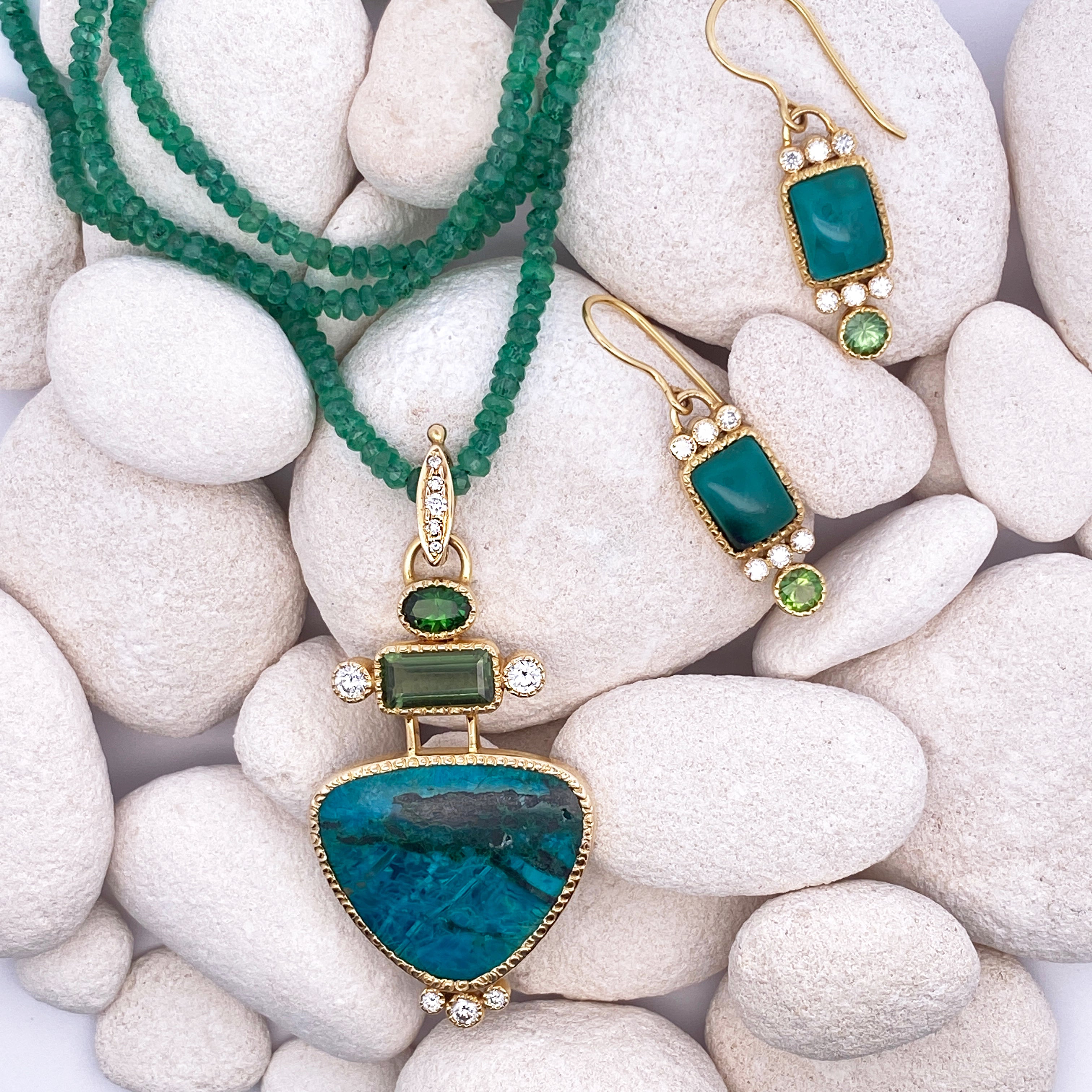 Green gemstone jewelry set including necklace and earrings on white coral pebbles