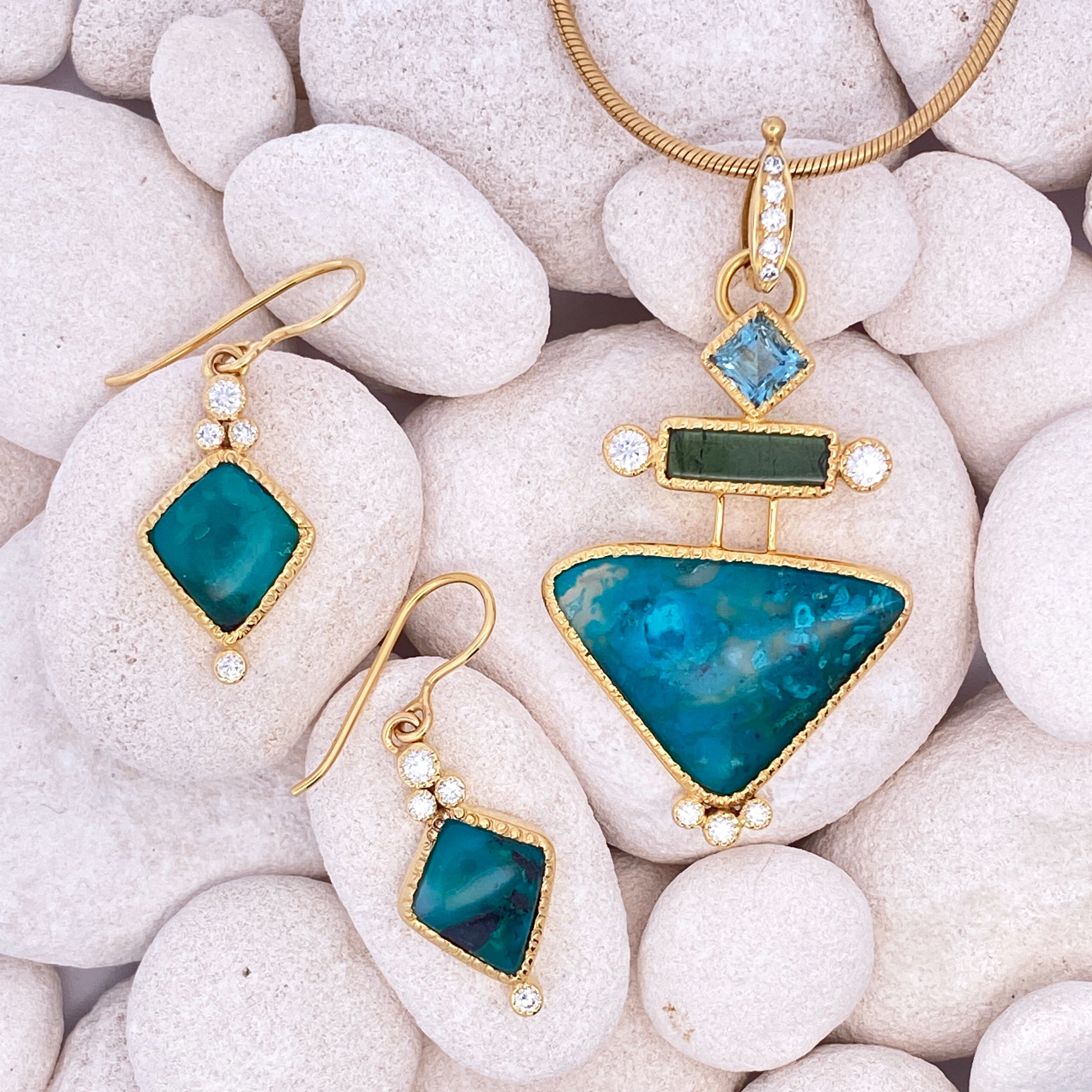 Gold jewelry with blue and green stones on white stones.