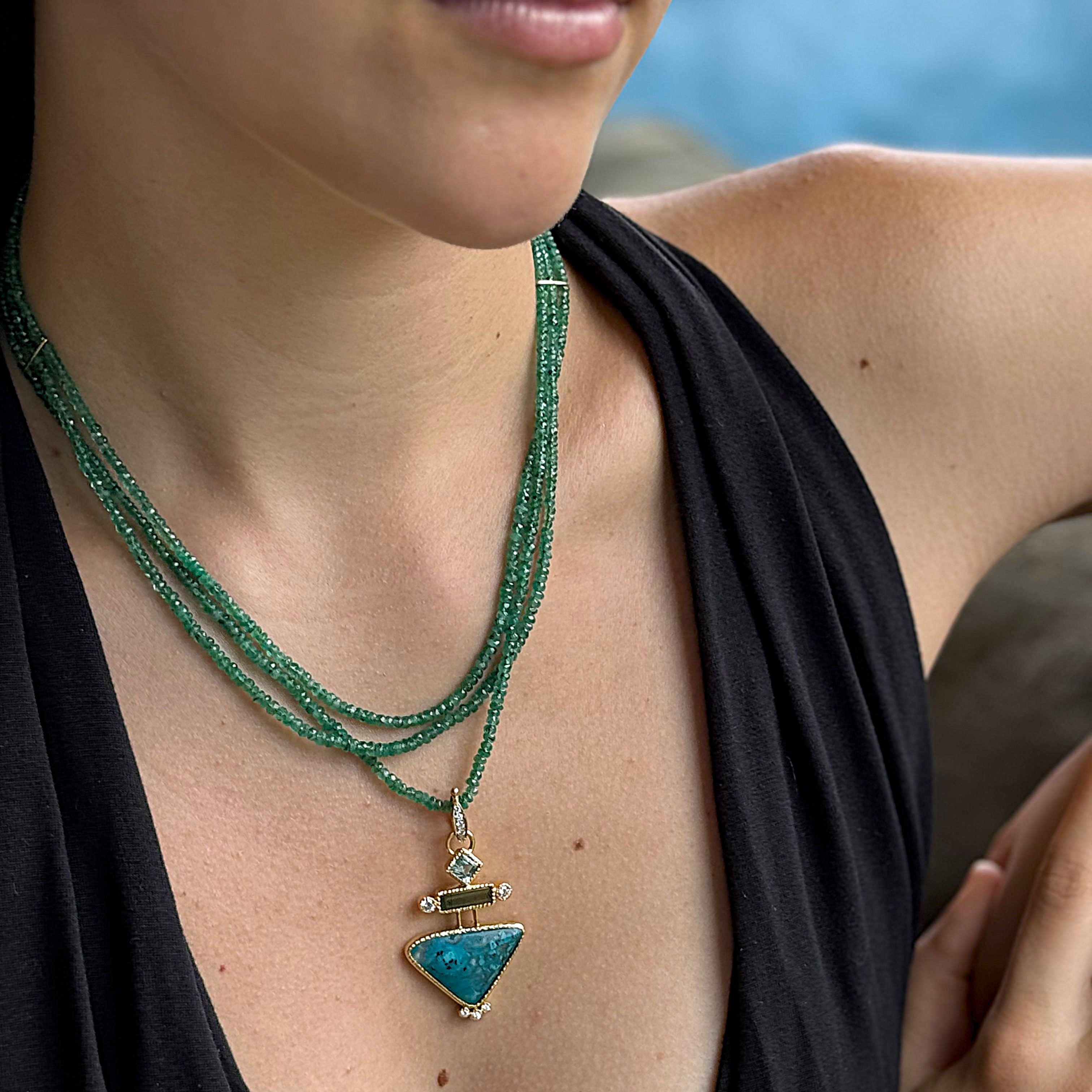 Close-up of a woman wearing a green beaded necklace with a blue pendant against a blurred natural background.