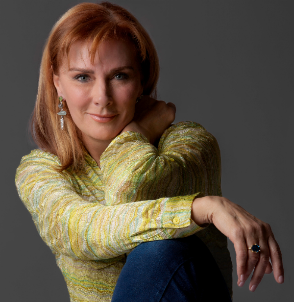 Q Evon wearing a patterned shirt and blue jeans against a gray background