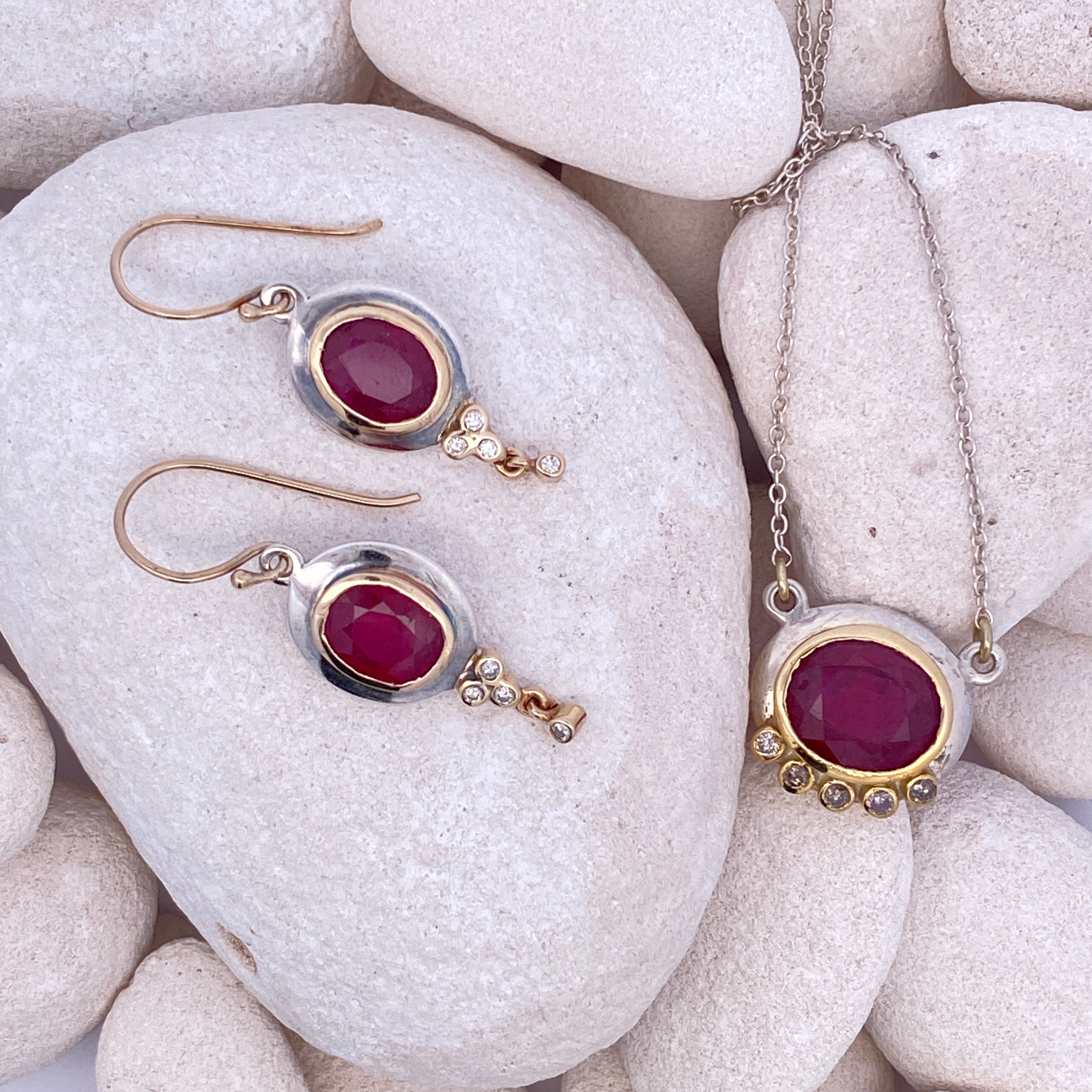 Jewelry set with red ruby gemstones with silver, gold, and diamond accents on white stones 