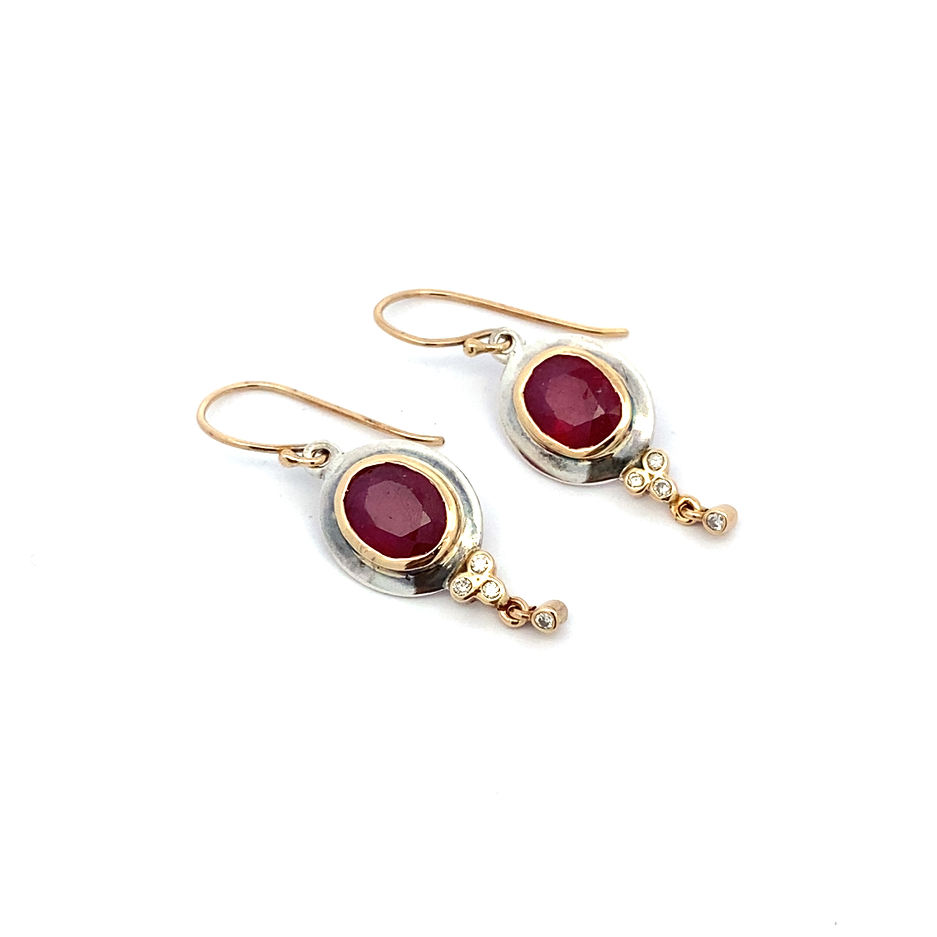 Pair of gold and silver earrings with red gemstones on a white background