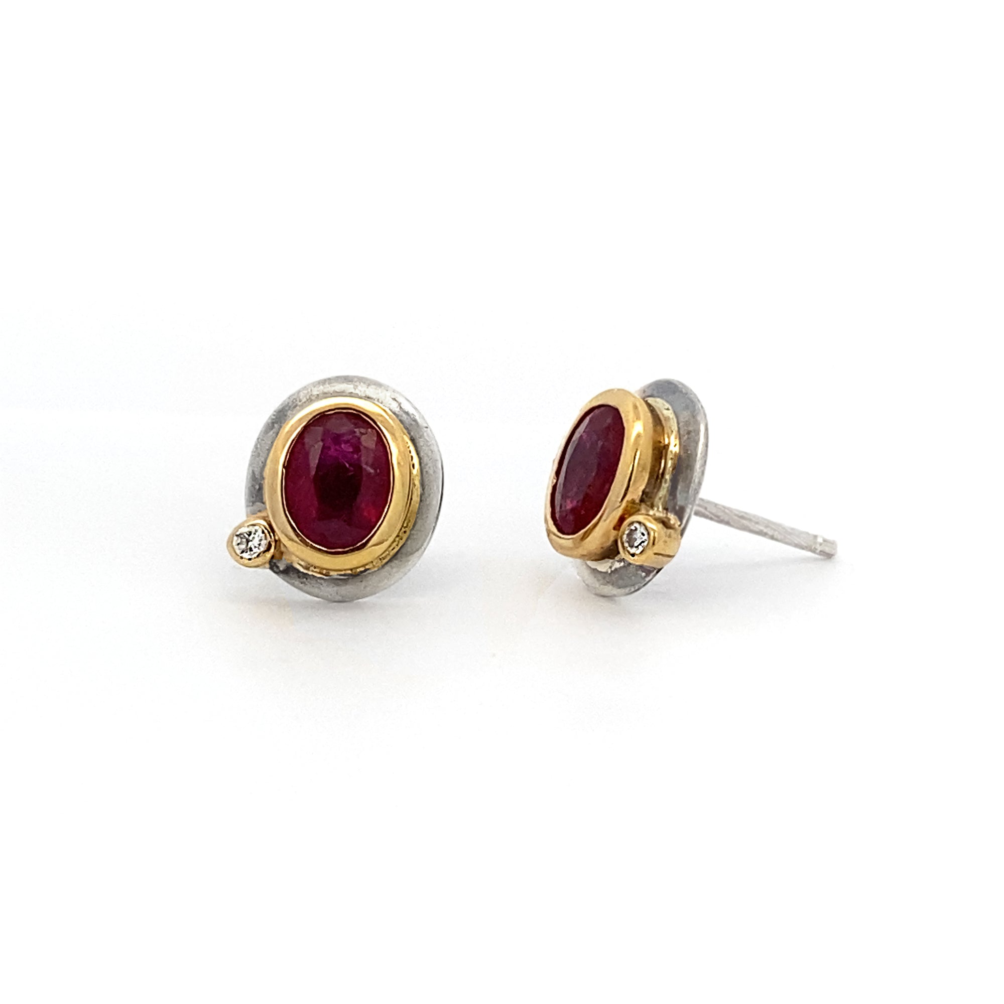 Pair of earrings with red gemstones and gold and silver accents on a white background