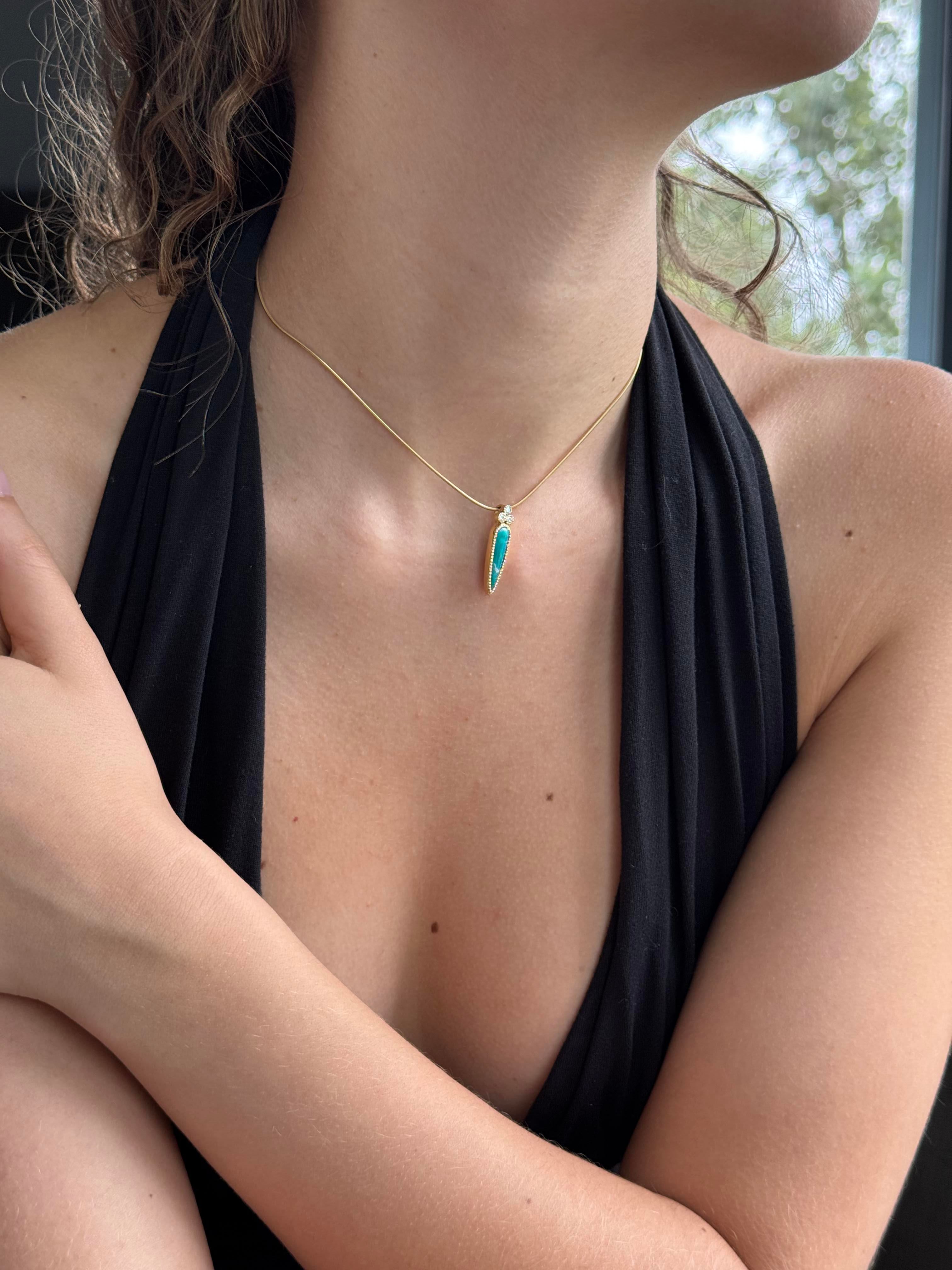 Person wearing a black top with a gold and green necklace, sitting outdoors.
