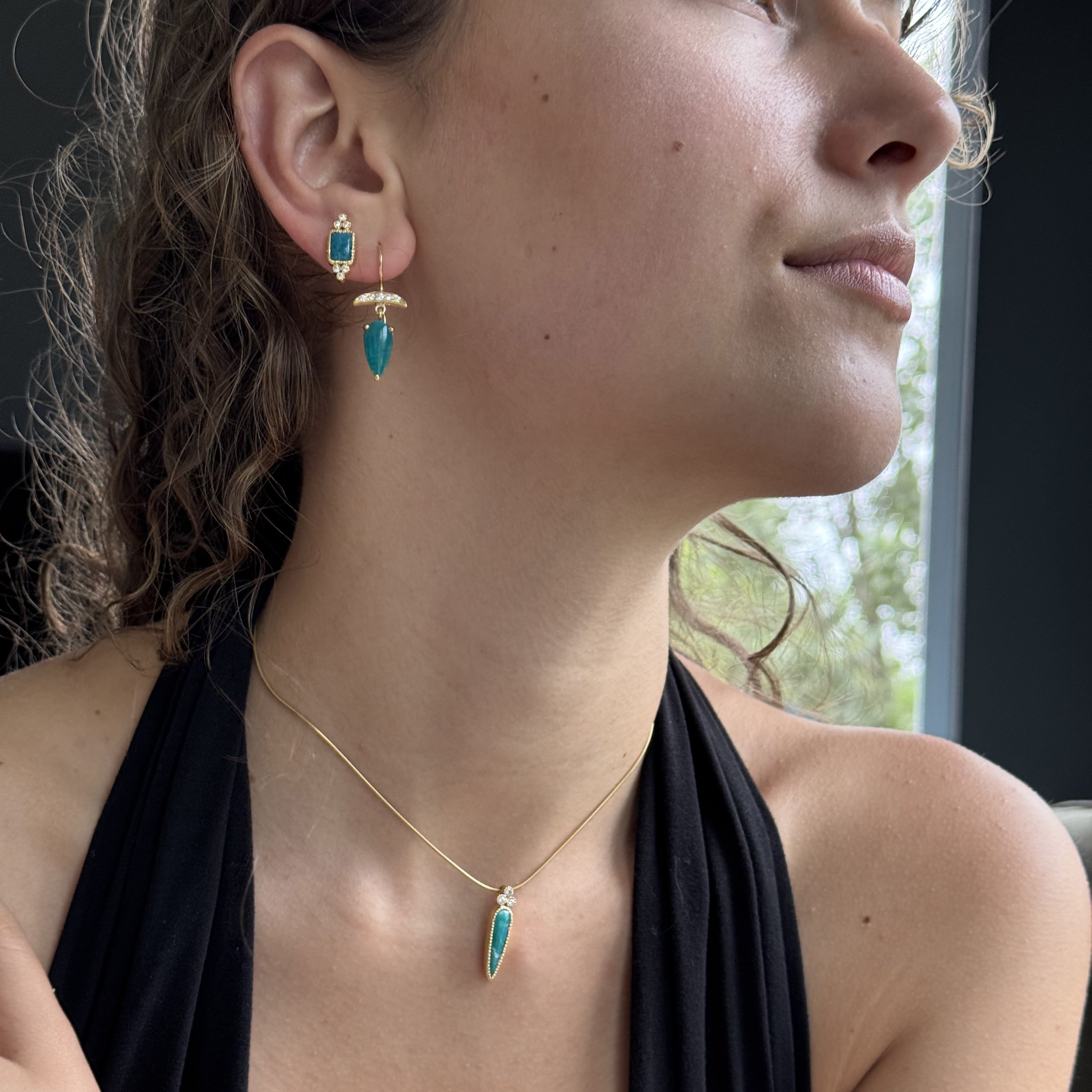 Close-up of a woman wearing gold and turquoise jewelry.