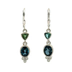 A pair of silver leverback drop earrings featuring a small green trillion tourmalines, an oval dark london blue topaz surrounded by a textured setting, and a small cluster of diamonds at the bottom.