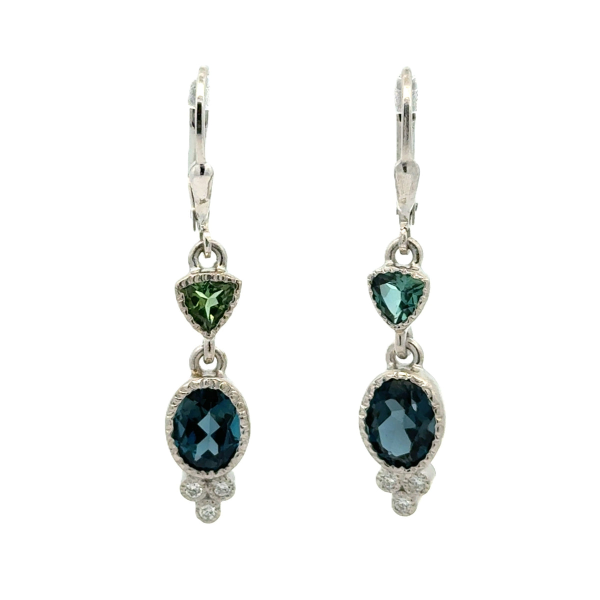 A pair of silver leverback drop earrings featuring a small green trillion tourmalines, an oval dark london blue topaz surrounded by a textured setting, and a small cluster of diamonds at the bottom.