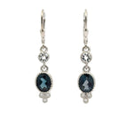 A pair of silver leverback drop earrings featuring oval dark London blue topaz gemstones, accented with round clear tourmalines, on a plain white background.