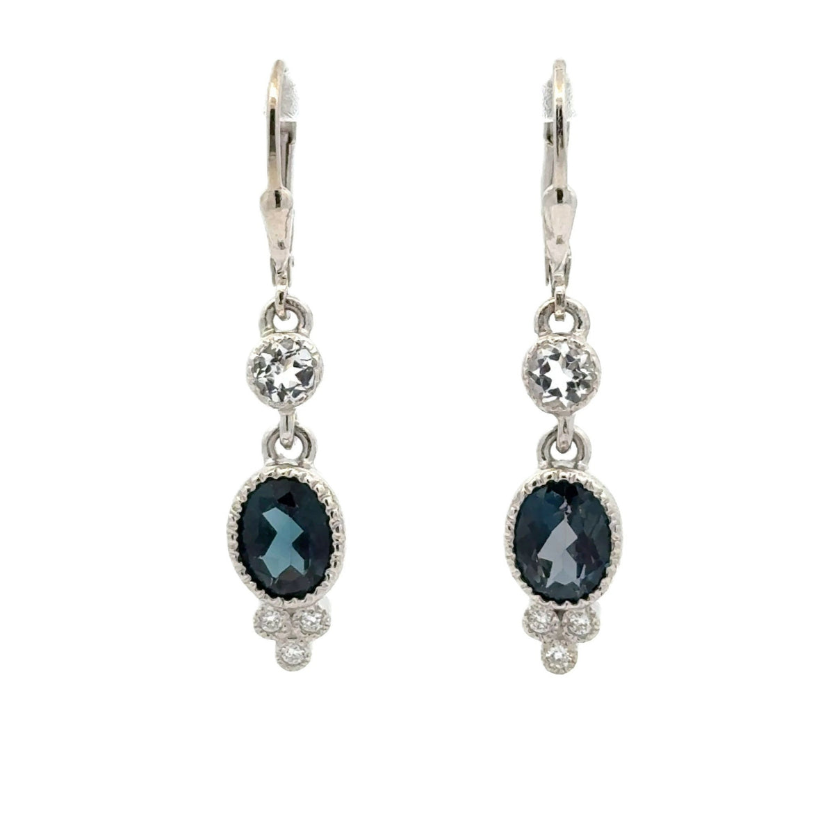 A pair of silver leverback drop earrings featuring oval dark London blue topaz gemstones, accented with round clear tourmalines, on a plain white background.