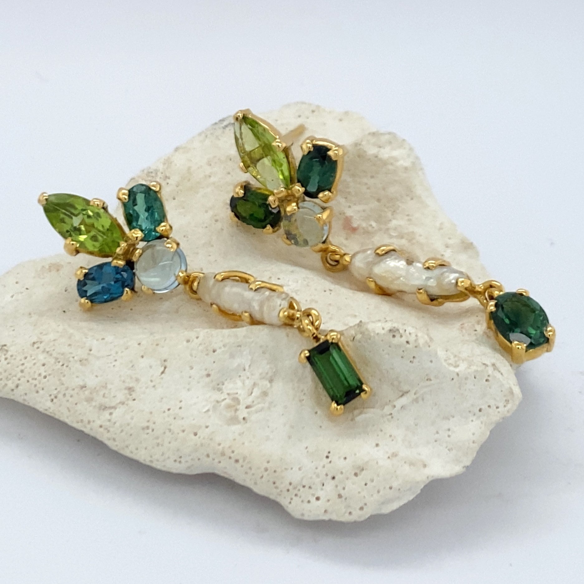 Pair of earrings with multiple green gemstones on a white background